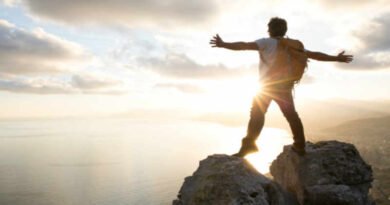 Jovem no topo de uma montanha vendo o horizonte vitorioso