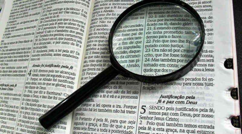 lupa posta sobre as letras de uma Bíblia aberta