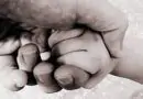 Uma mão adulta segurando a mão de uma criança